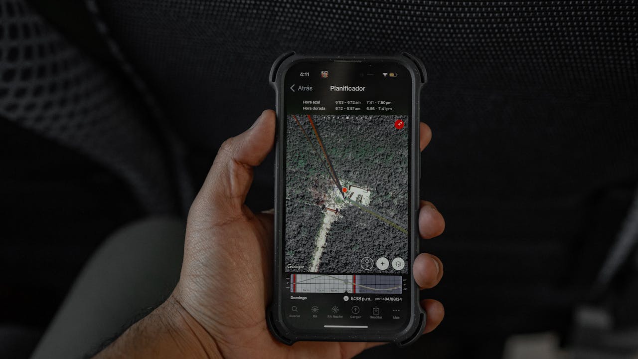 Close-up of a hand holding a smartphone displaying a GPS map in a vehicle interior.